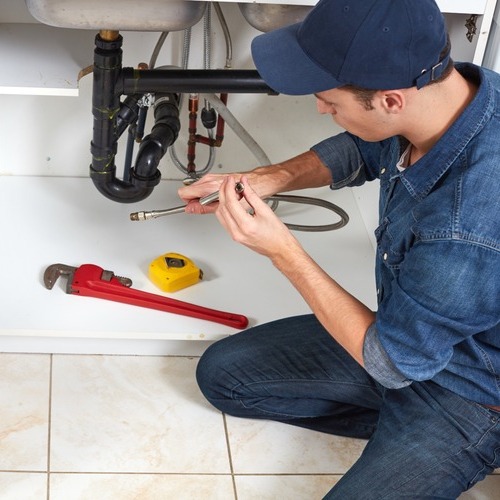 a plumber repairing pipes under a sink