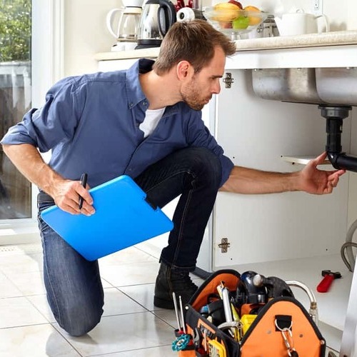 A Plumber Check Pipes under a Sink.