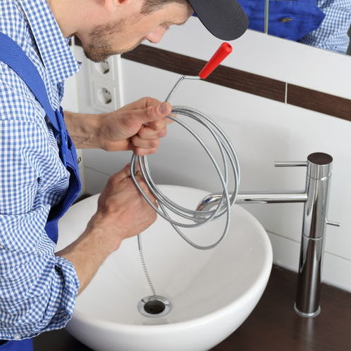 A plumber clears a drain.