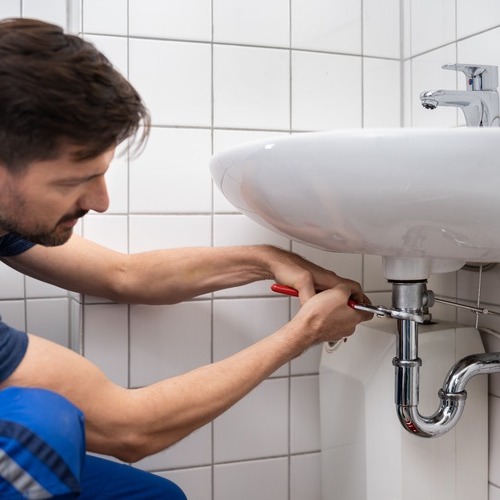 A plumber repairs a sink.